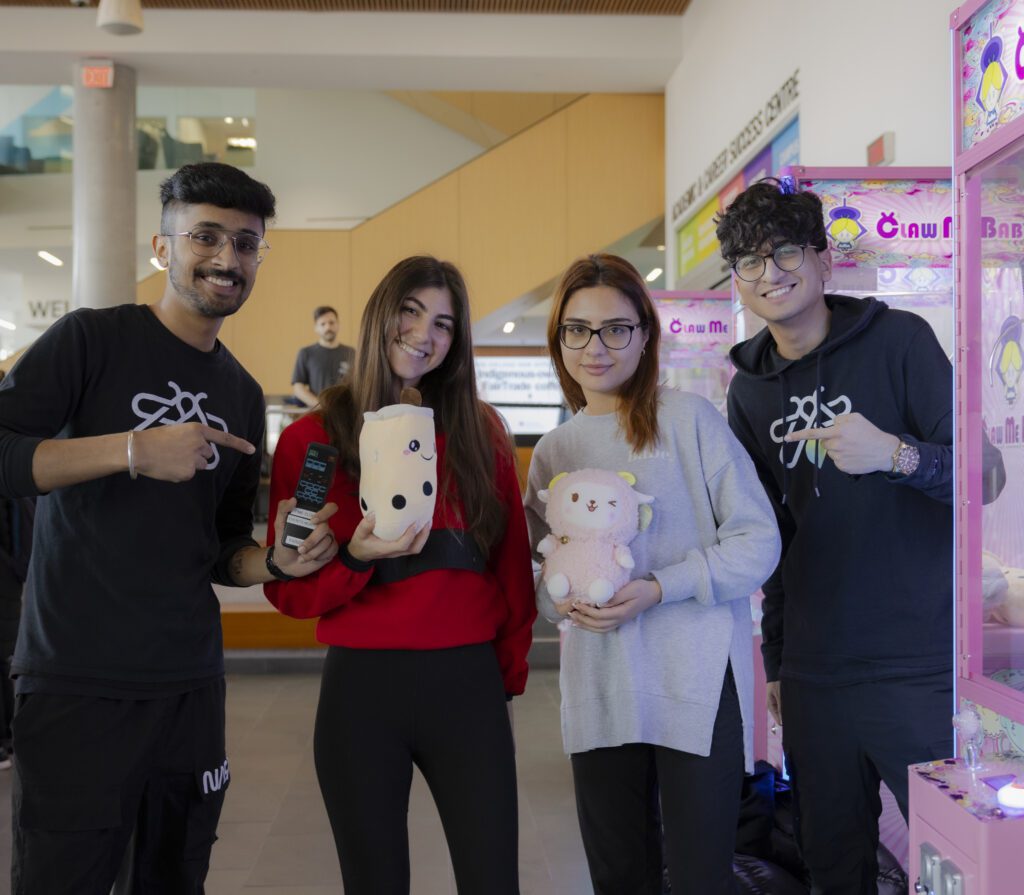 Four students smiling while two of them hold a plushie each