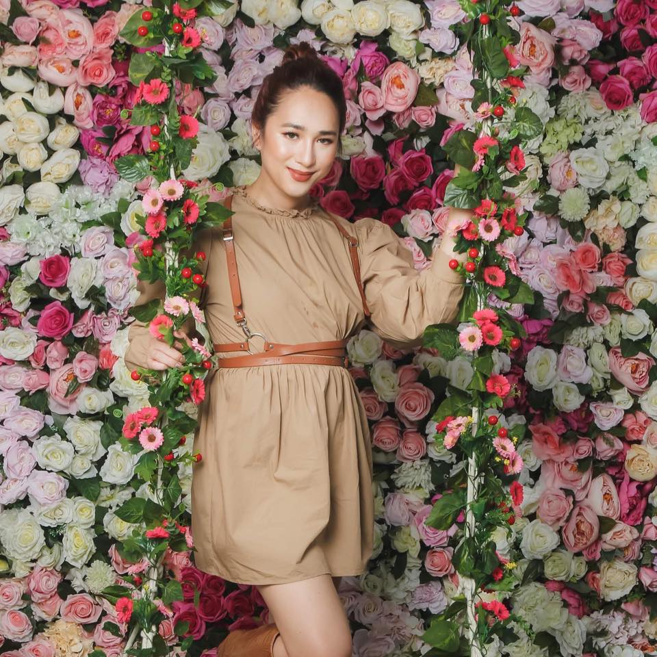 A picture of a standing girl with a flower background.