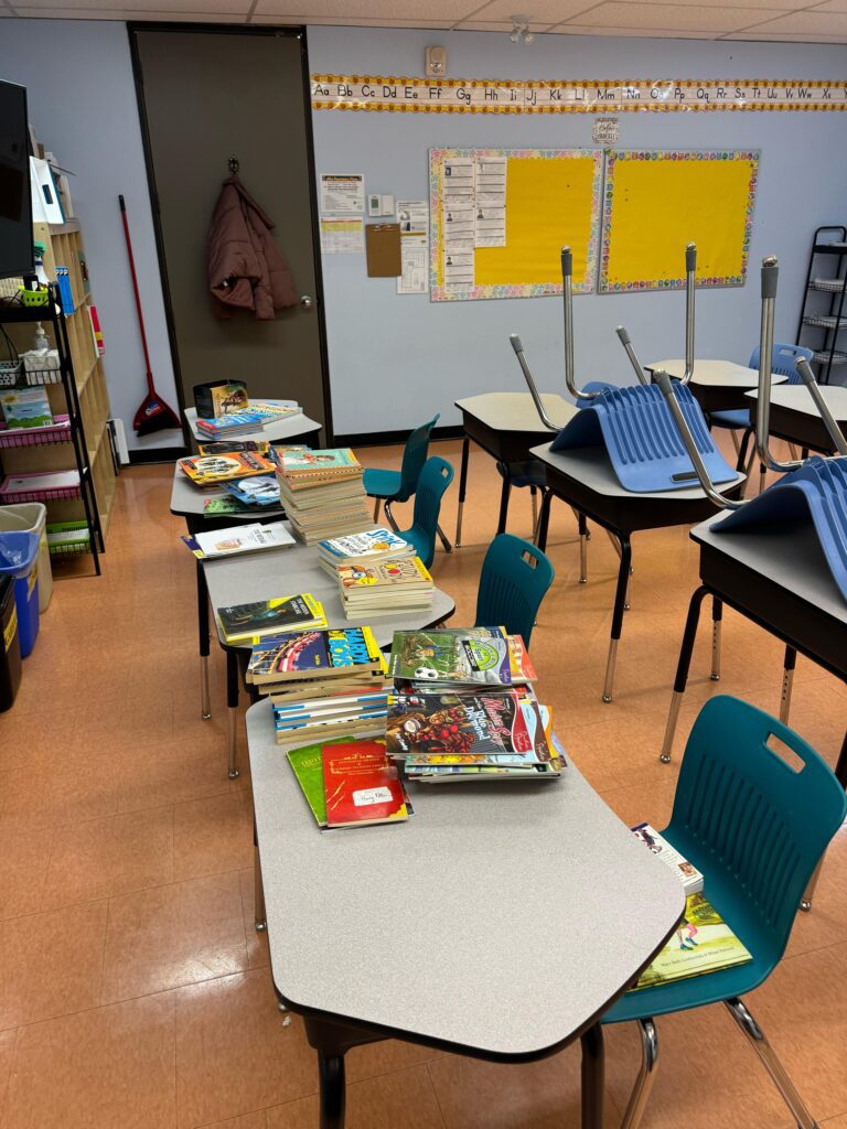 Books are scattered across various desks in a classroom.