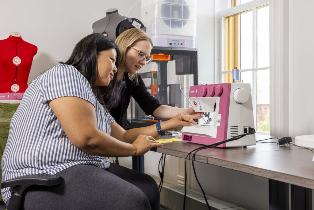 Two people in the idea lab using the sewing and embroidery tools at Lakeshore.