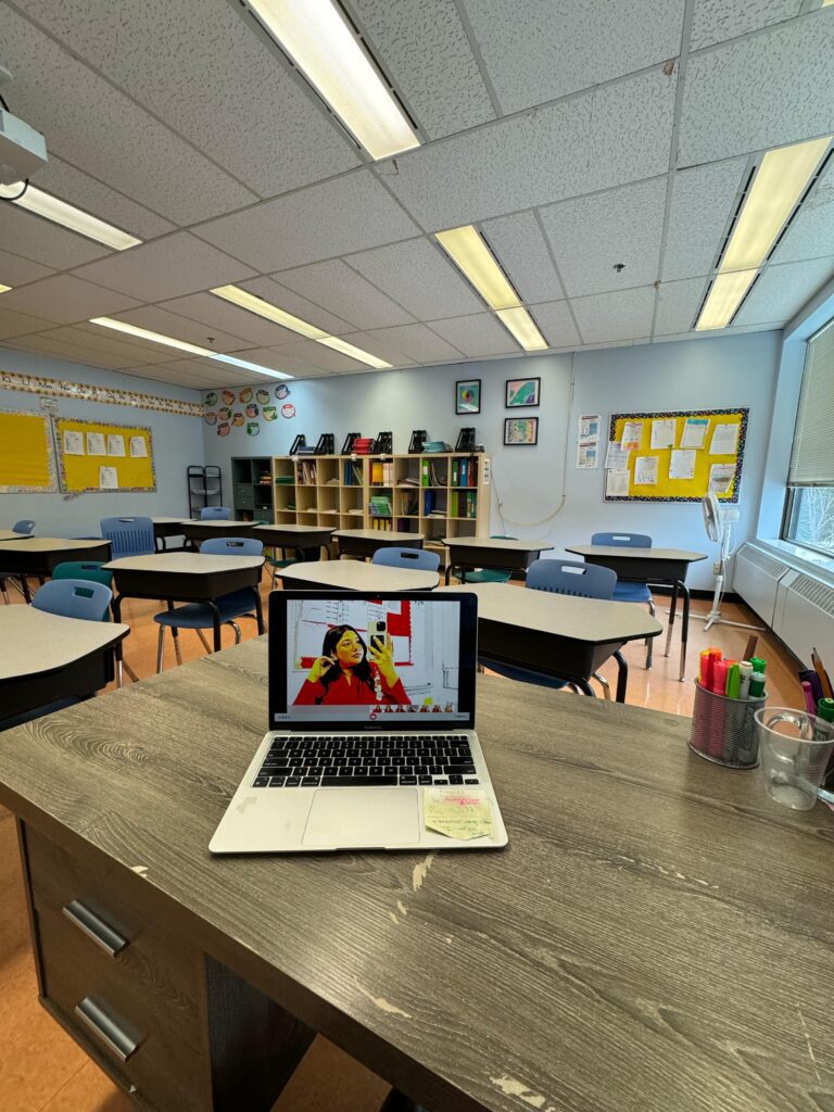 A laptop placed on a desk in the classroom.