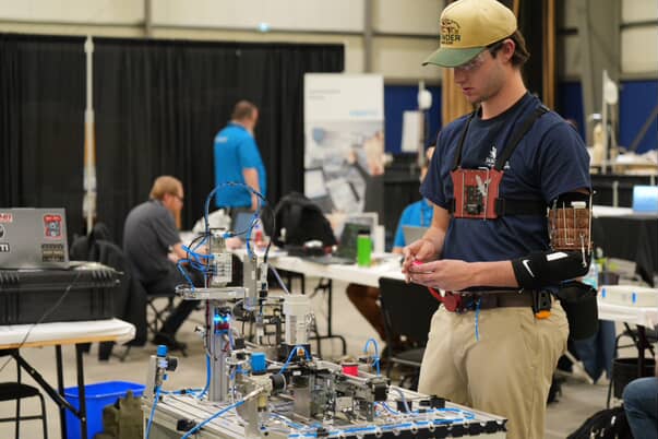 Student with a brown bracer and safety harness controlling the machinery.