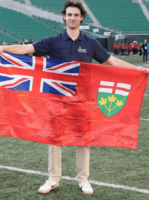 Student holding up the Ontario flag on a football field.