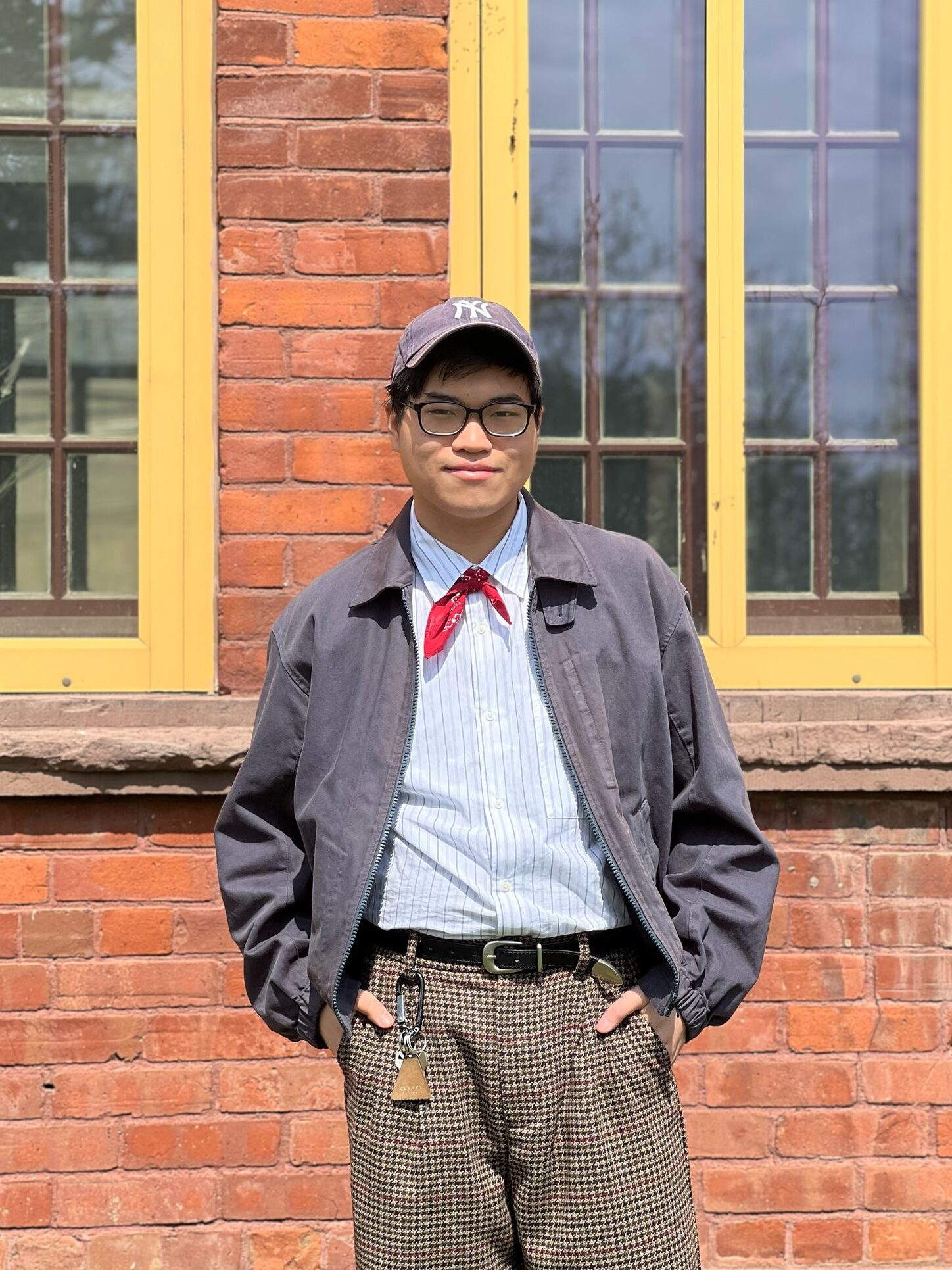 Student wearing plaid pants, stripes shirt, jacket and bandana