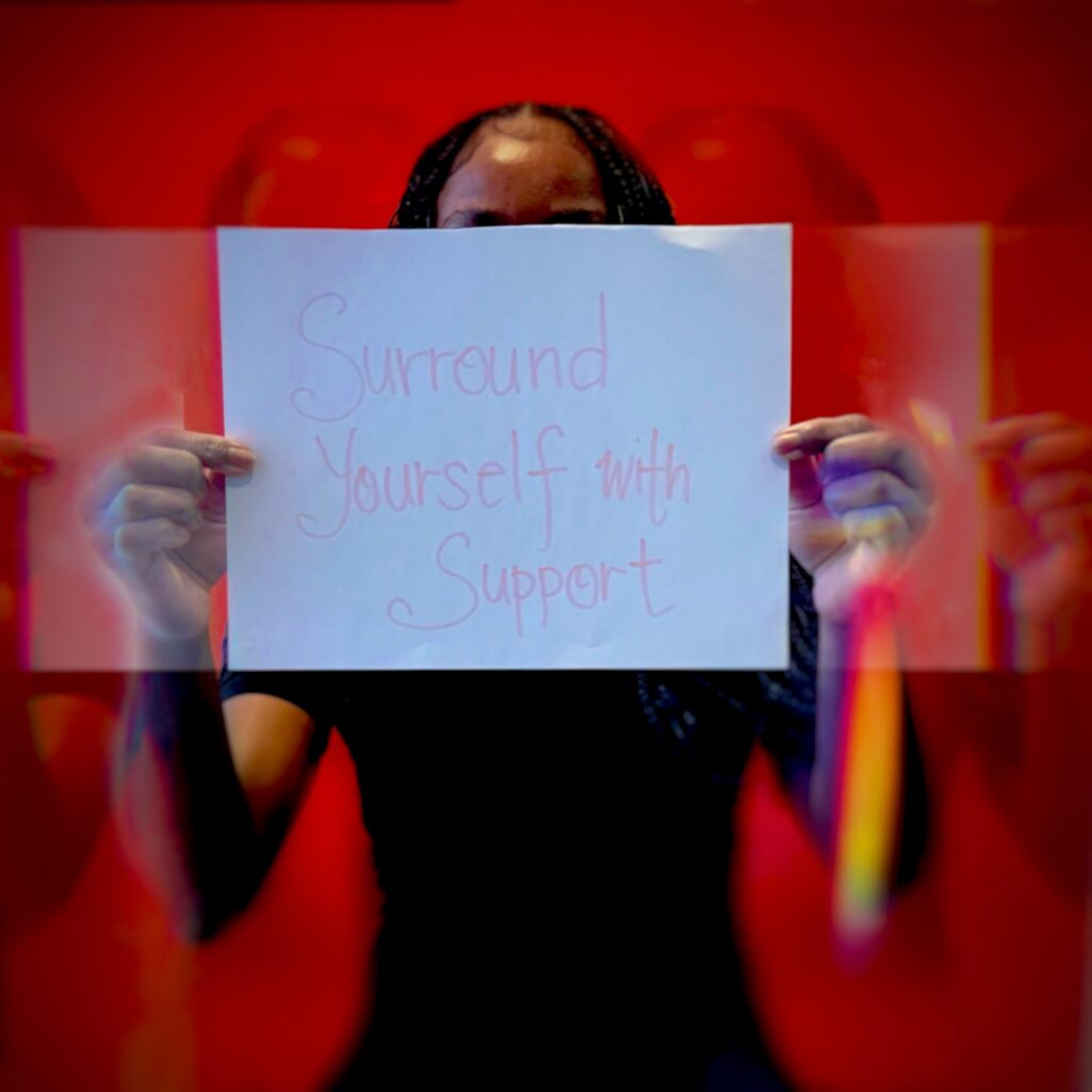 A girl holding a paper saying "Surround Yourself With Support".