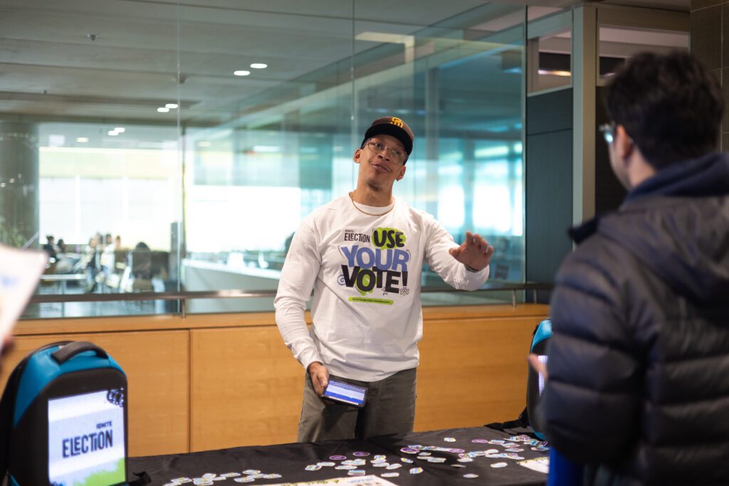 A brand ambassador is speaking to a student; he’s making gestures with his left hand.