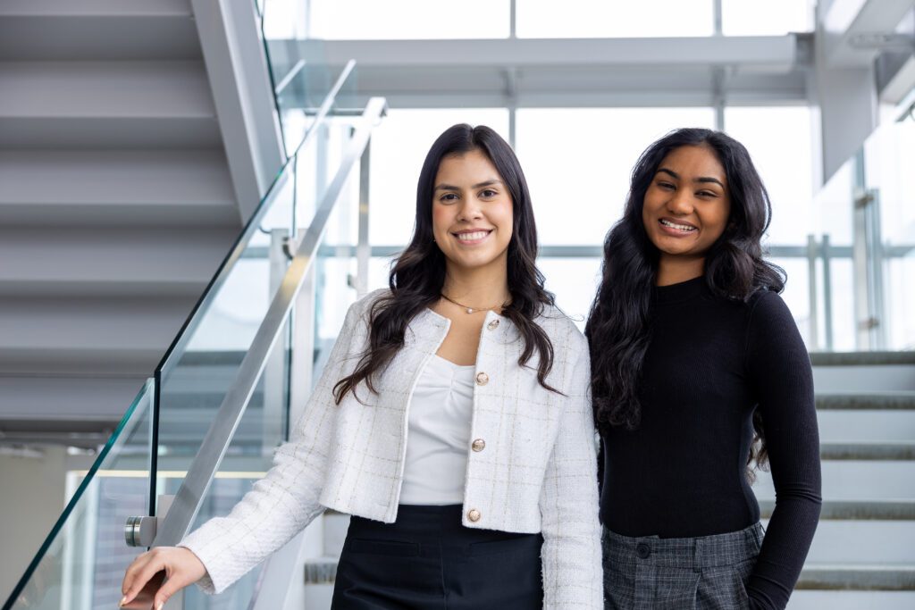 Two women are standing together on a staircase. 