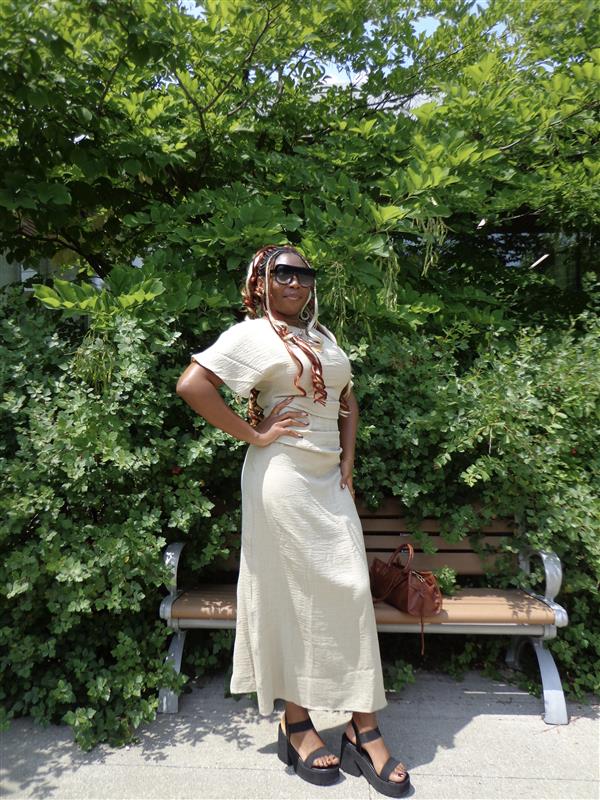 A woman is standing outdoors and posing.