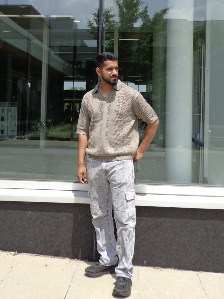 A man is posing outdoors in the sun.