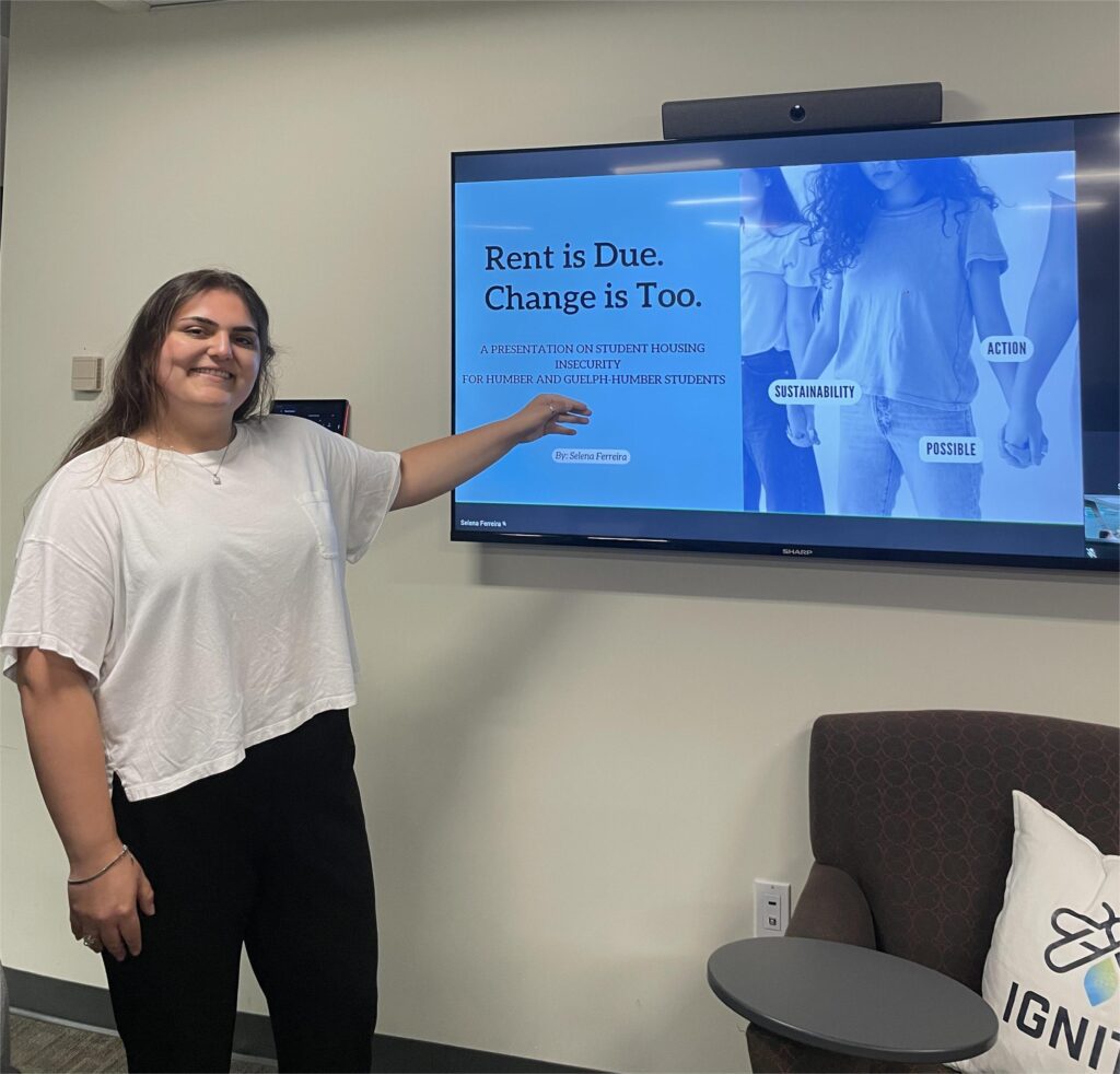 A woman is smiling and pointing towards the TV screen.