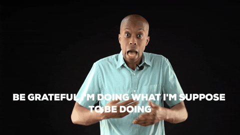 A man in a light blue shirt speaks against a black background with the text, "BE GRATEFUL I'M DOING WHAT I'M SUPPOSE TO BE DOING."