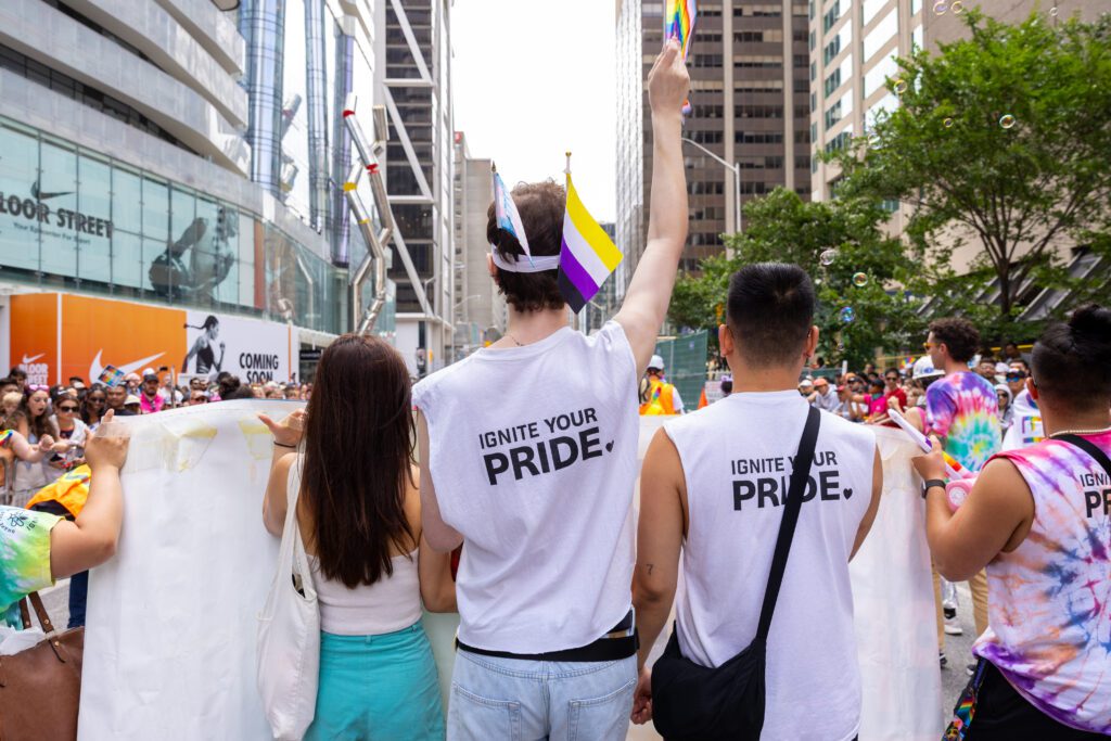 A group of people raising flags and participating in the Pride march. 