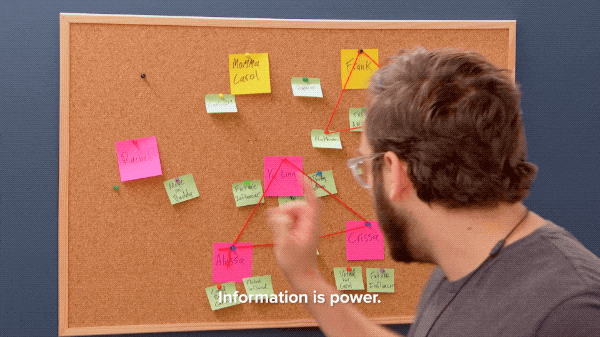 a man poinitng at a board with sicky notes on it saying "information is power."