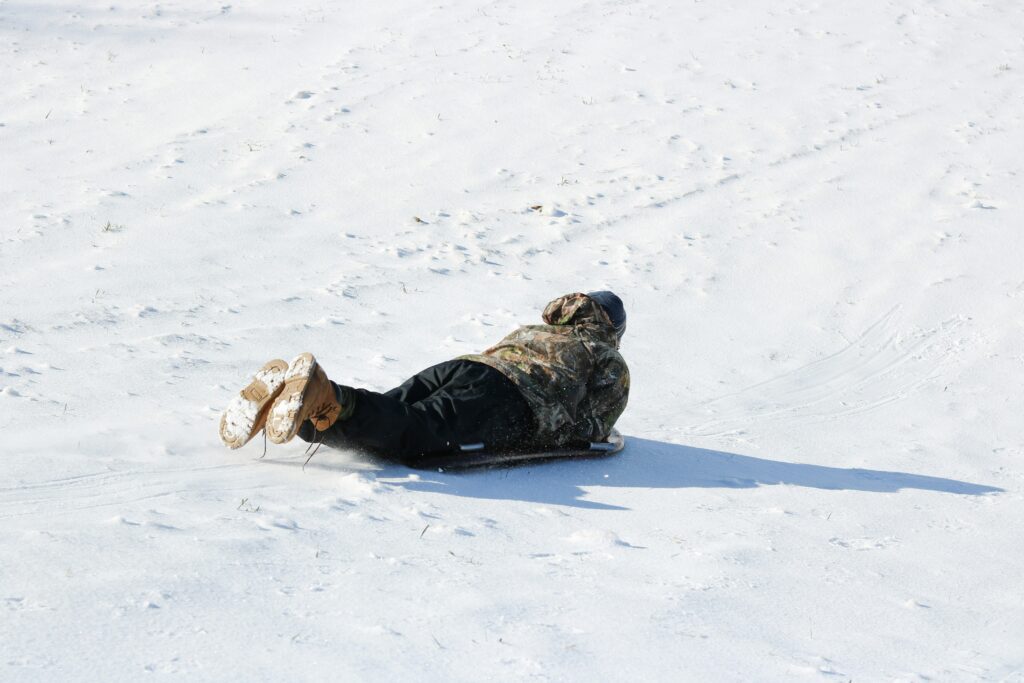 A person on their belly tobogganing down a hill.