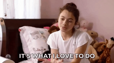 A young girl sitting on a bed with stuffed animals behind her, speaking with the caption "IT'S WHAT I LOVE TO DO".
