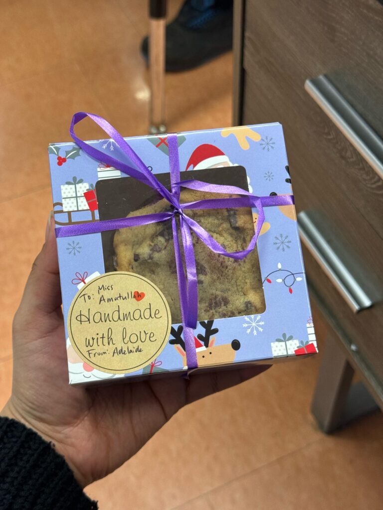 A box with a handwritten note in the corner that reads, "To: Miss Amatullah. Handmade with love. From: Adelaide," accompanied by a small treat inside.