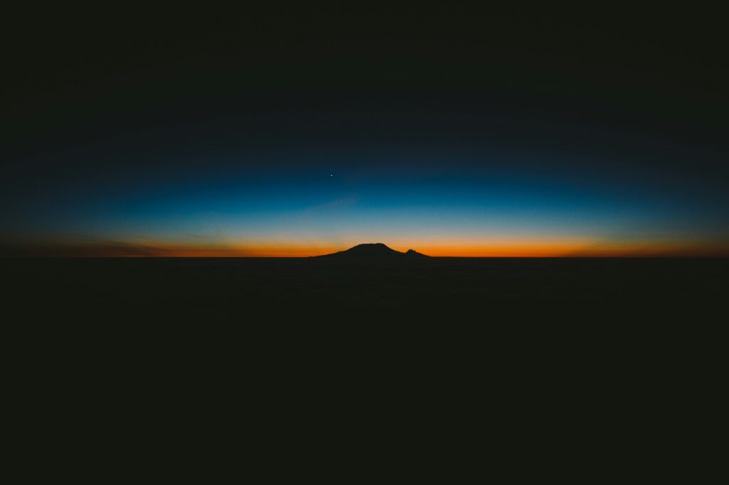 A dark day with a slim blue and orange horizon in the distance. 