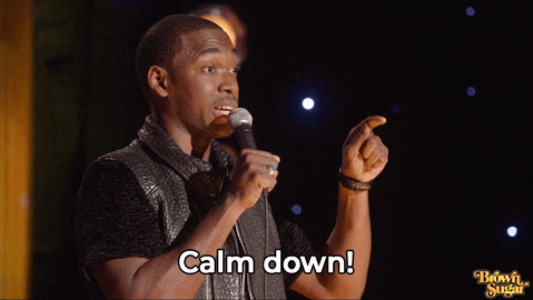 A man is holding the microphone and saying the words, "It's not that serious. Calm down!"