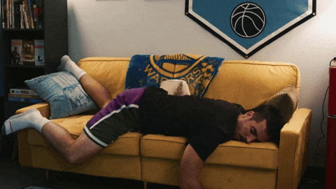 A man falls down while sleeping on the couch.