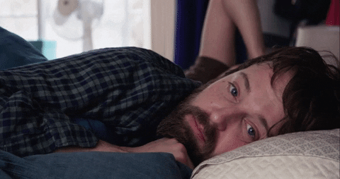 A man is lying on the bed with his eyes wide open.