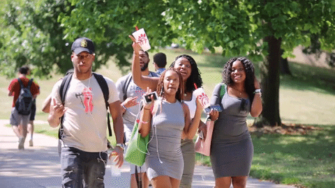 A group of friends are walking around the campus, waving their hands.