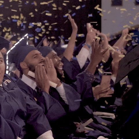 Graduates shouting joyously as confetti rains down on them.