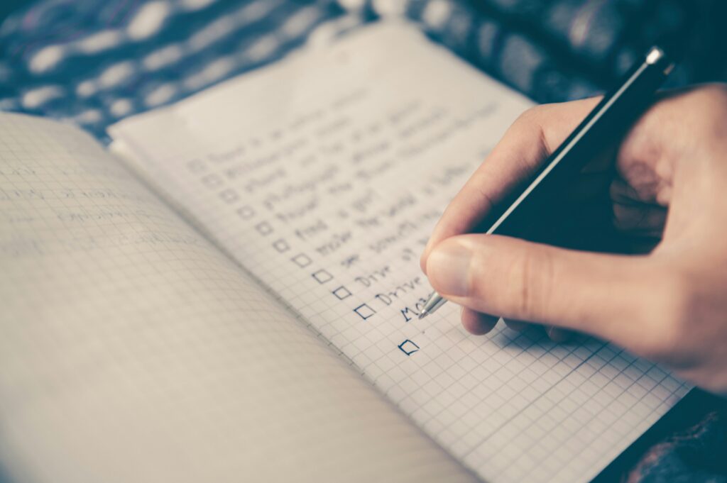 A notebook with someone writing a checklist.