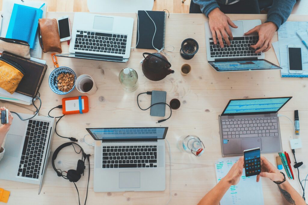 A table full of computers, headphones, phones and portable chargers.