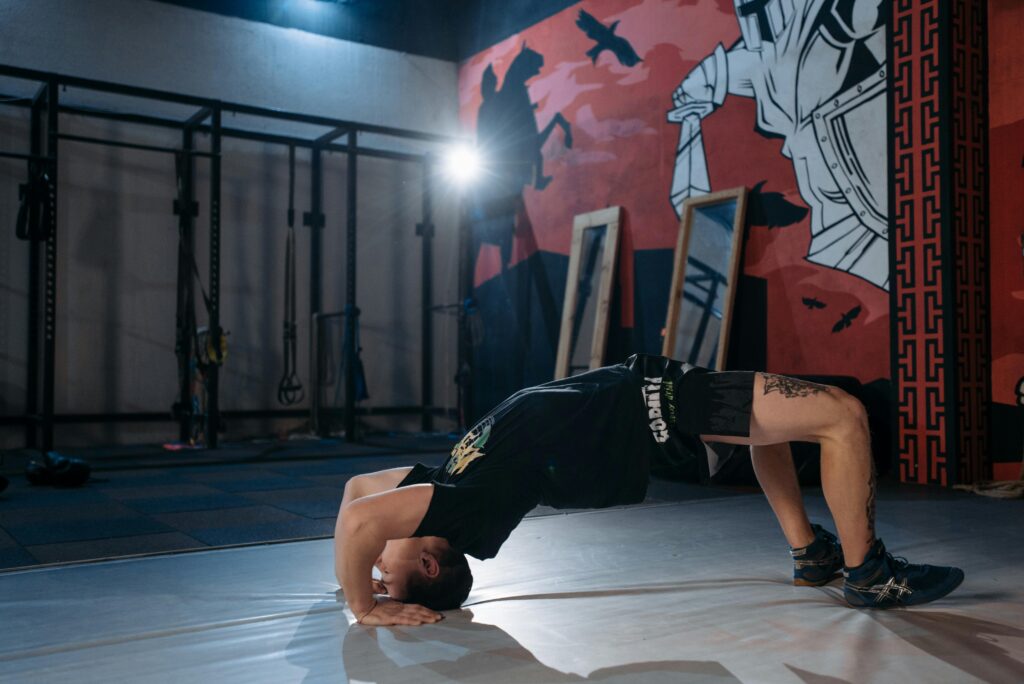 A person bending over backward into a bridge in a martial arts studio. 