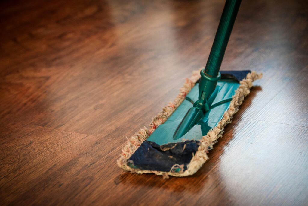A dirty mop pressing against a hardwood floor. 