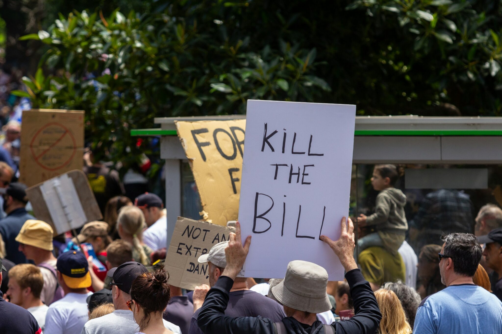 A picture of a crowd, primarily headshots, holding signs in protest with one sign prominently featured spelling "Kill the Bill".