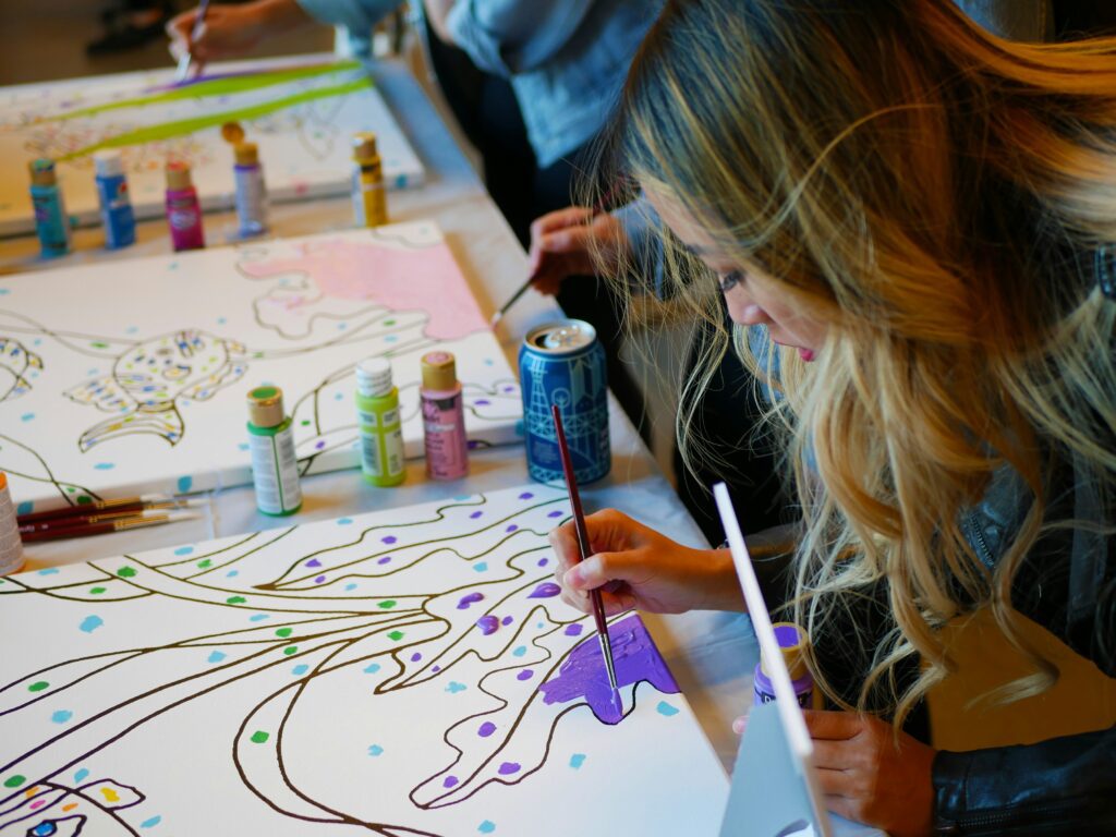 person taking photo of woman doing paint artwork 