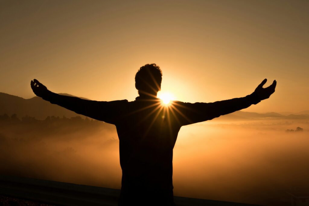 silhouette photo of man on a cliff during a sunset