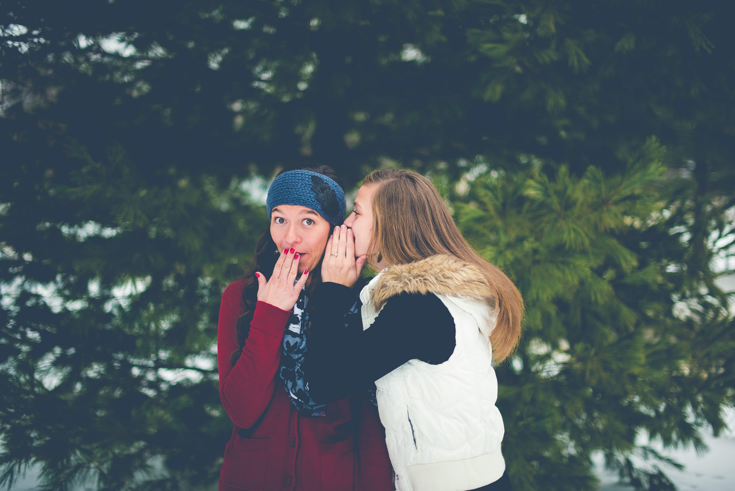 A woman whispering into the ear of another woman