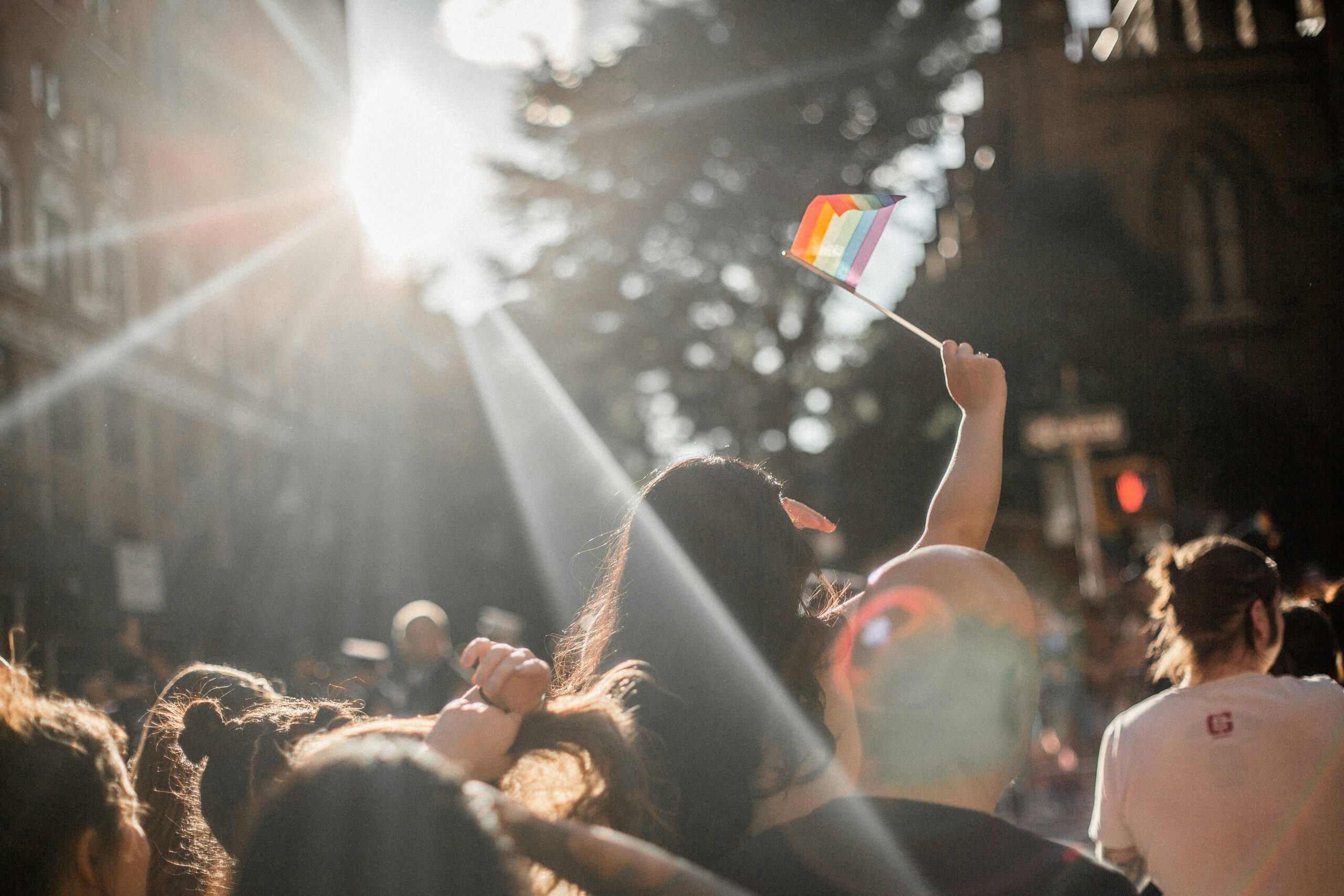 a parade with a woman holding up a small Pride flag