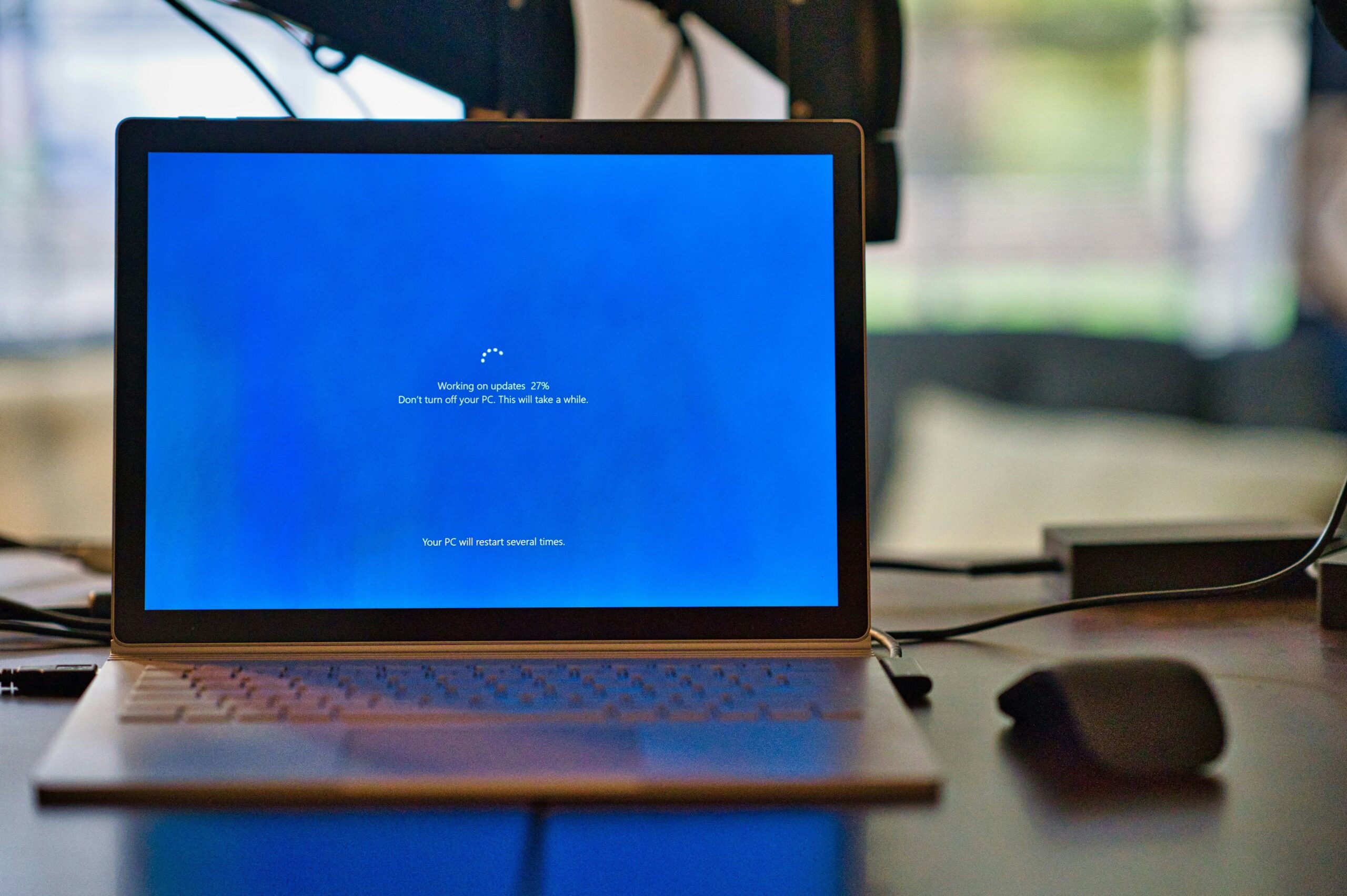 A laptop on a desk displays a progress screen for Windows updates at 72%.