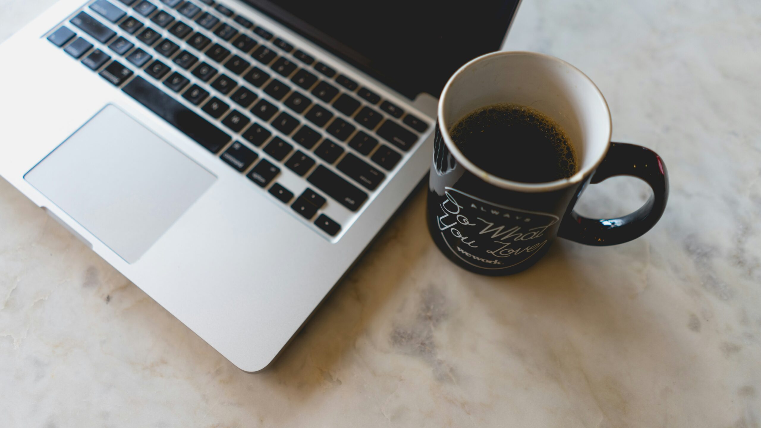 Picture of a coffee cup next to a laptop