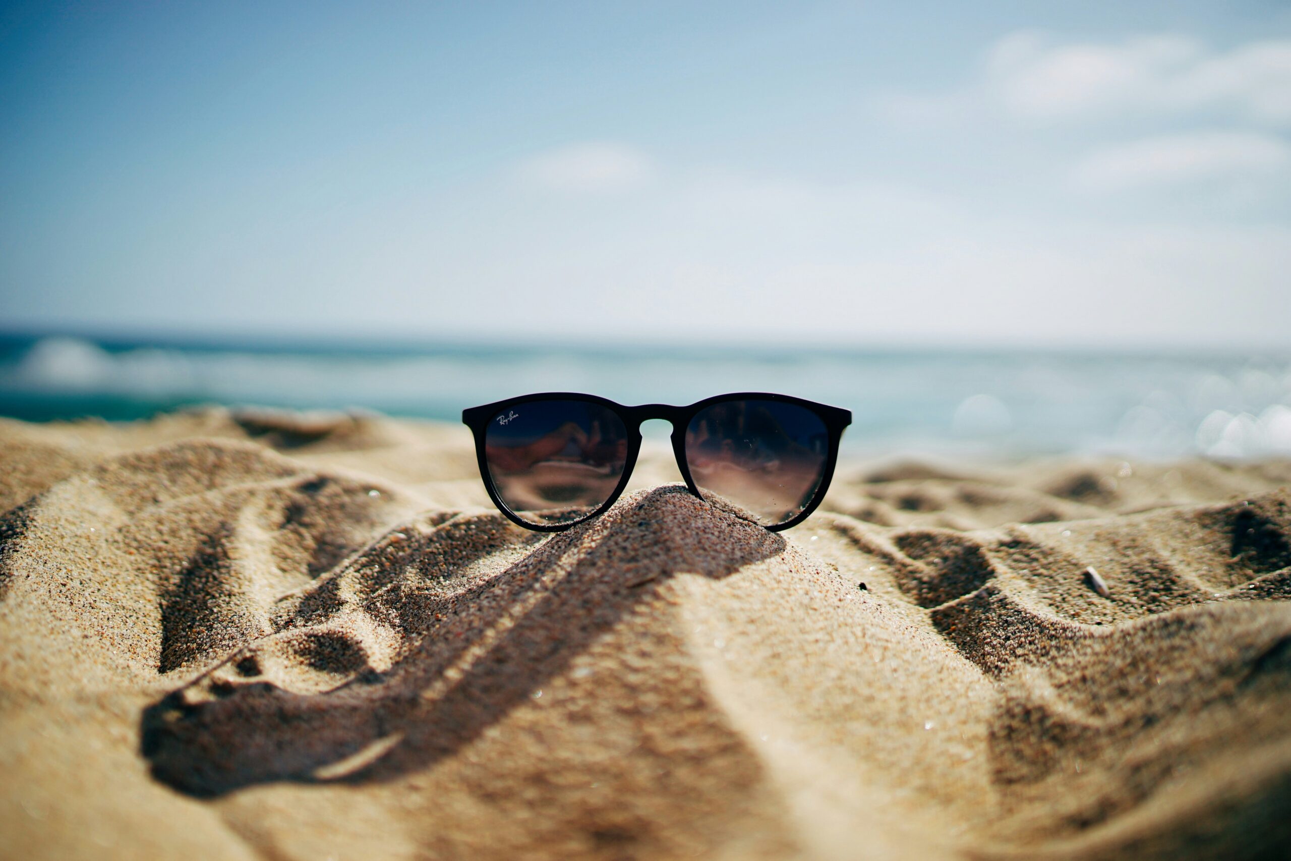 A sunny beach with sunglasses kept on sand
