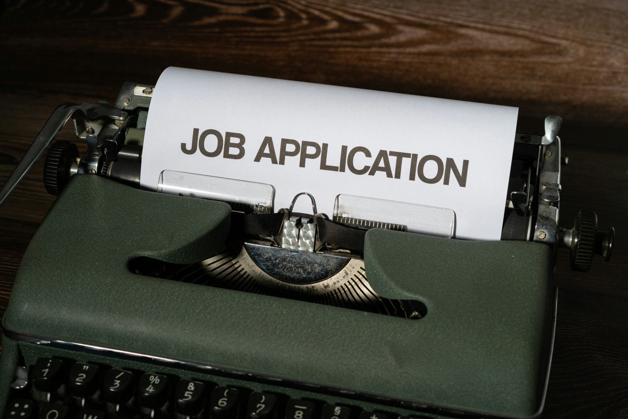 A typewriter with paper coming out the top with JOB APPLICATION written as the title.