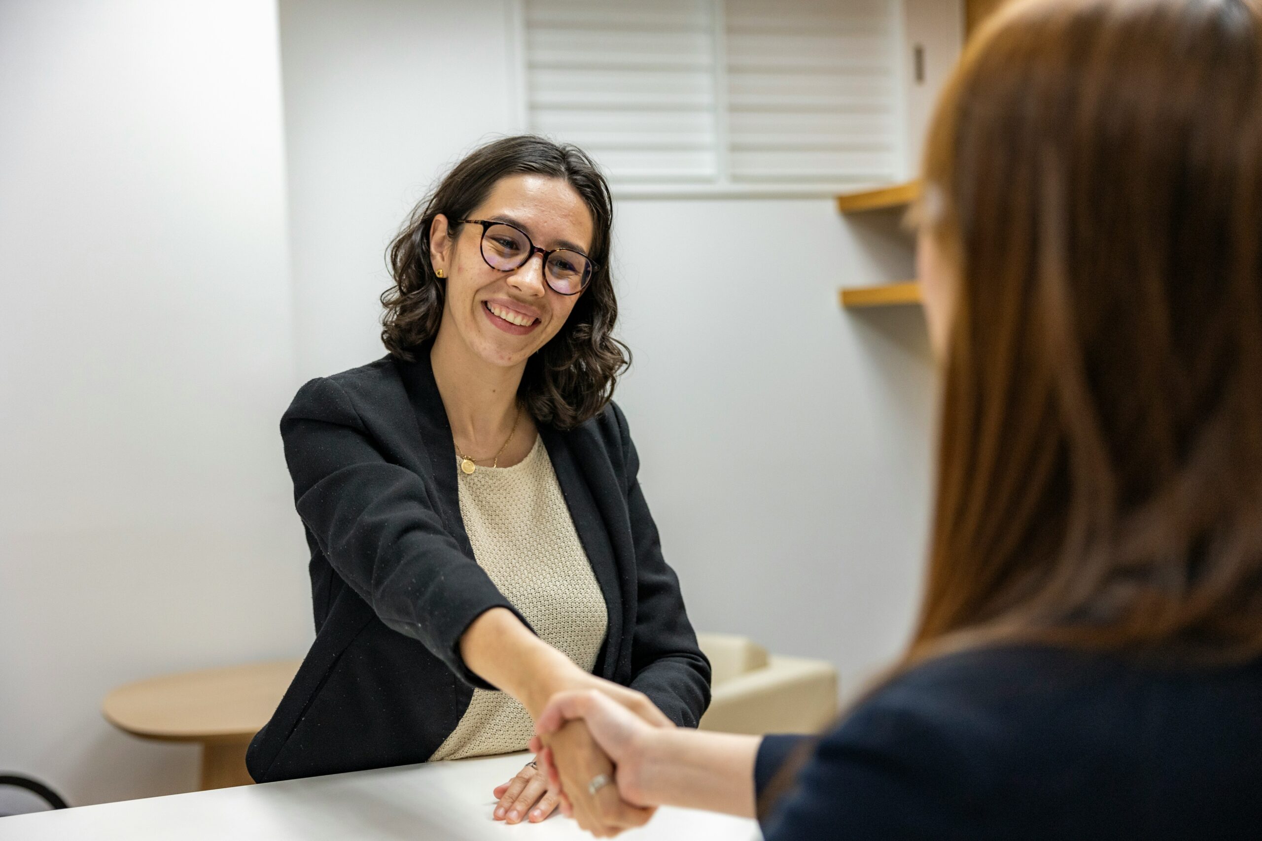 A woman is shaking hands with another woman.