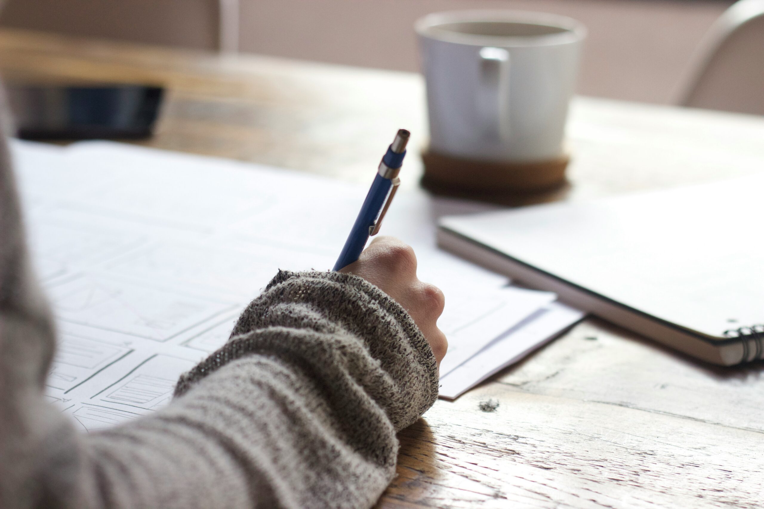 A close up of a hand writing in a notebook