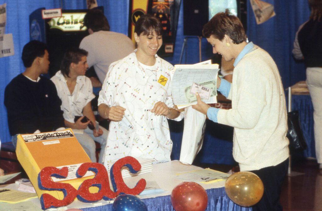 Photos of students at a SAC orientation table conversing with SAC staff in 1987.