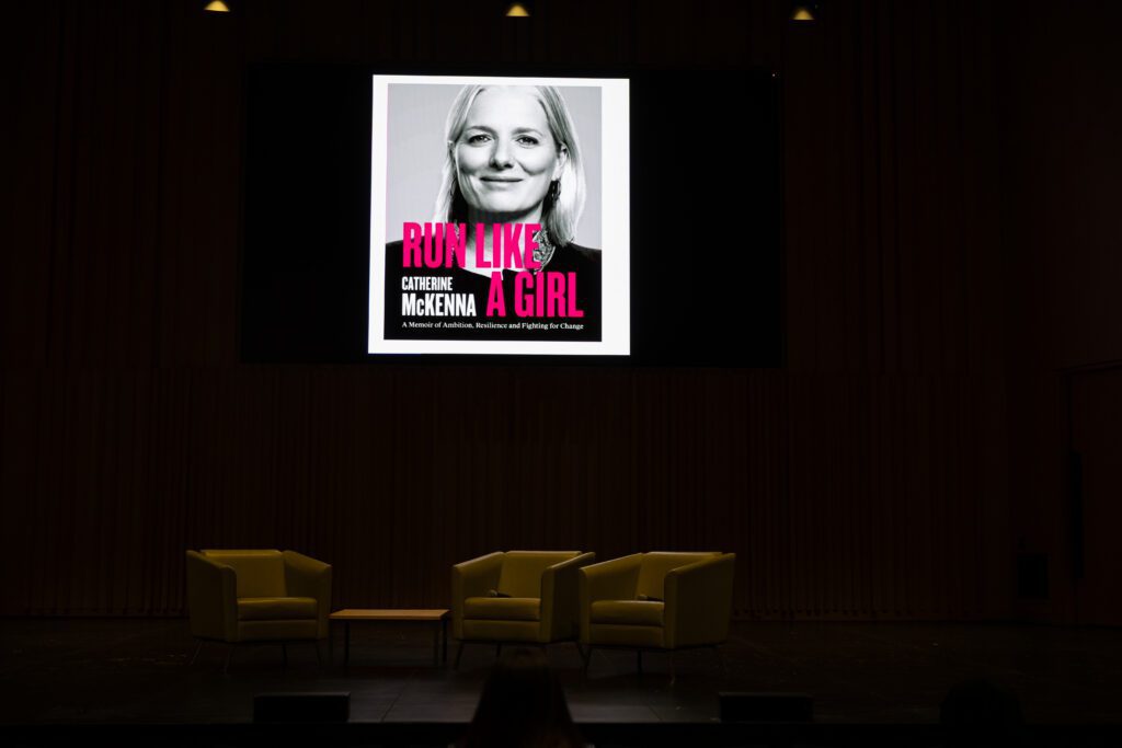 Stage background with the screen displaying Canterine McKenna's memoir "Run Like A Girl"