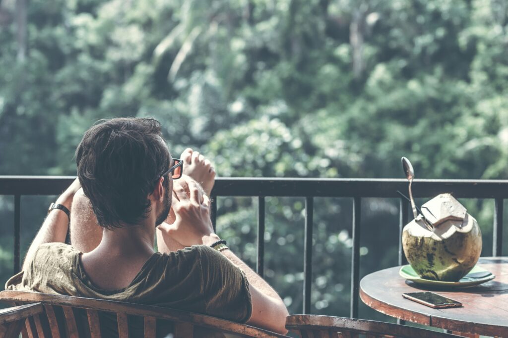 a man sitting in the balcony with an open coconut