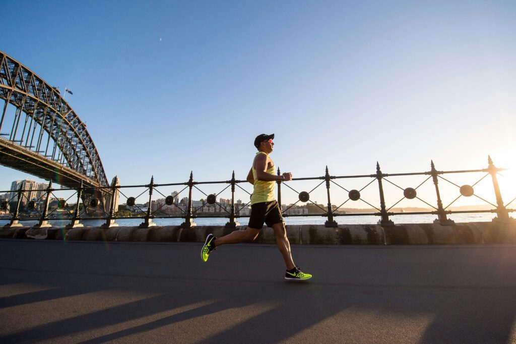 A man running on a sidewalk near a waterfront view