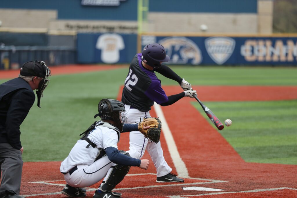 A person at bat on a baseball diamond swinging at a ball.