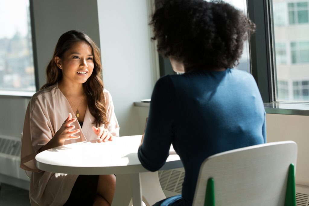 A person speaking confidently to another person sitting across from them.