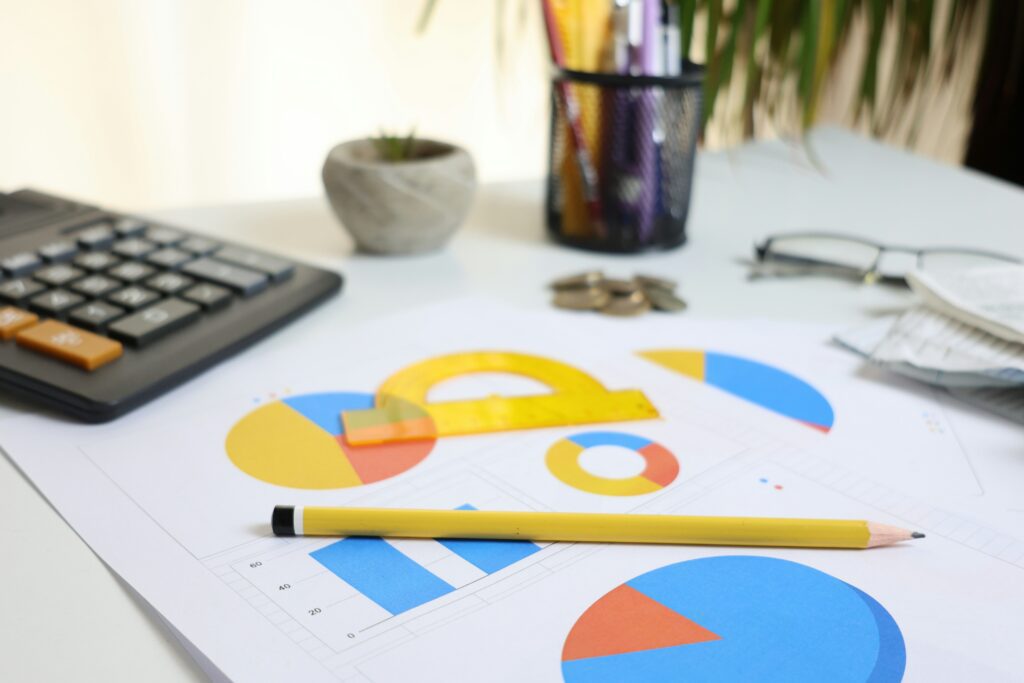 a table with papers that have graphs on them, a calculator and a pencil