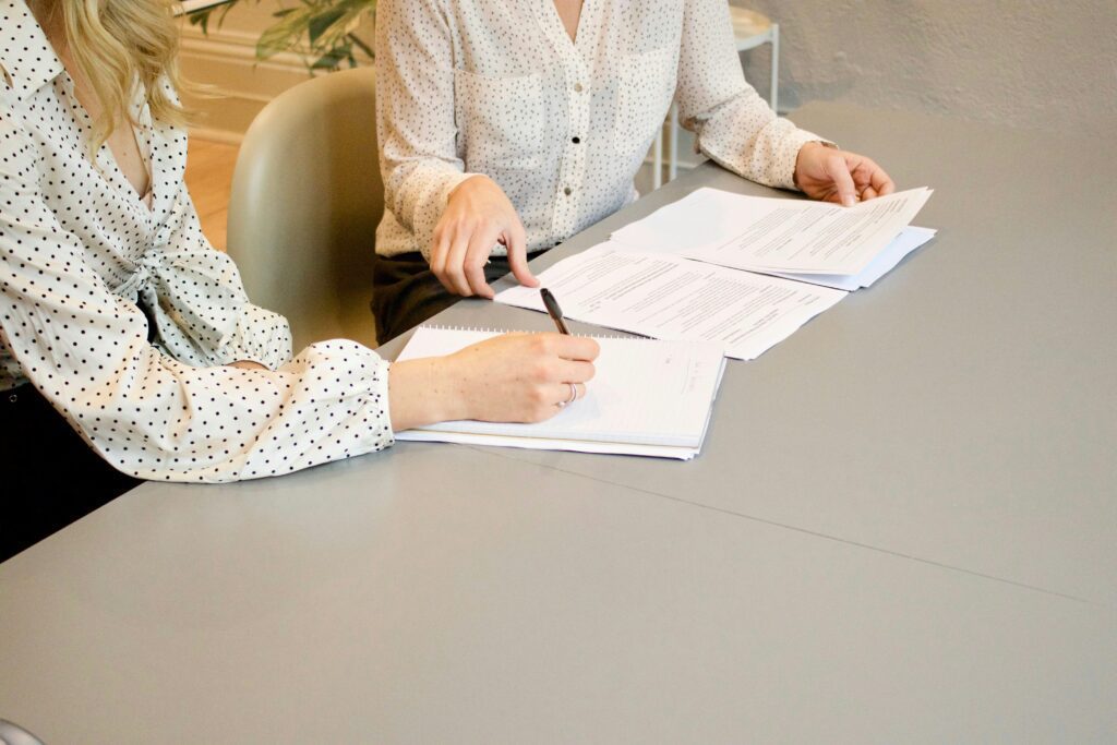 low shot of two people conversing while writing in a notebook.