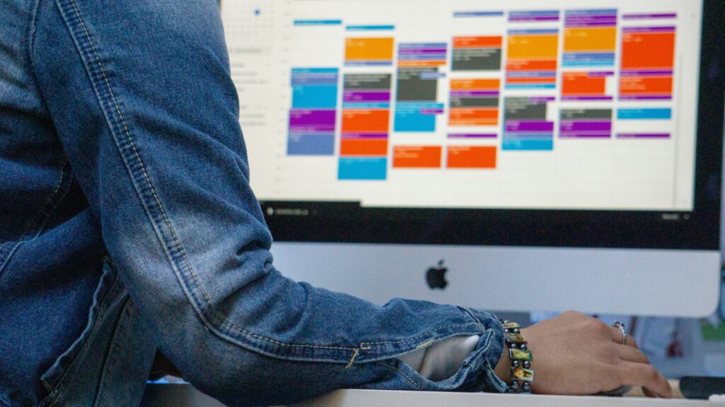 a monitor displaying a busy calendar with colour coded tasks